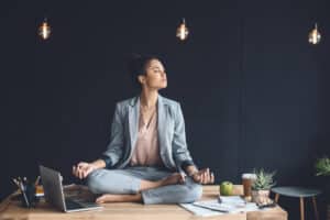 woman at work meditating to control stress and anxiety