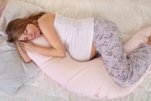 Pregnant woman sleeping with a body pillow