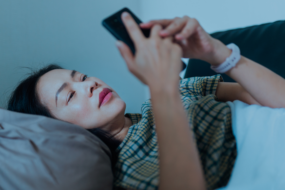 woman using her cel phone in bed