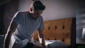 Man sitting on the edge of the bed looking tired